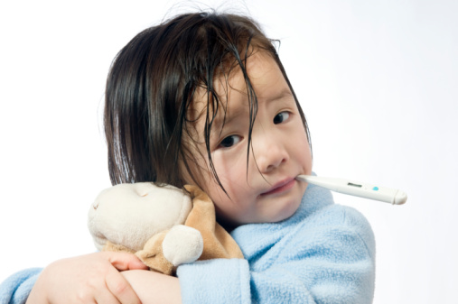 A young girl is sick and having her temperature taken.